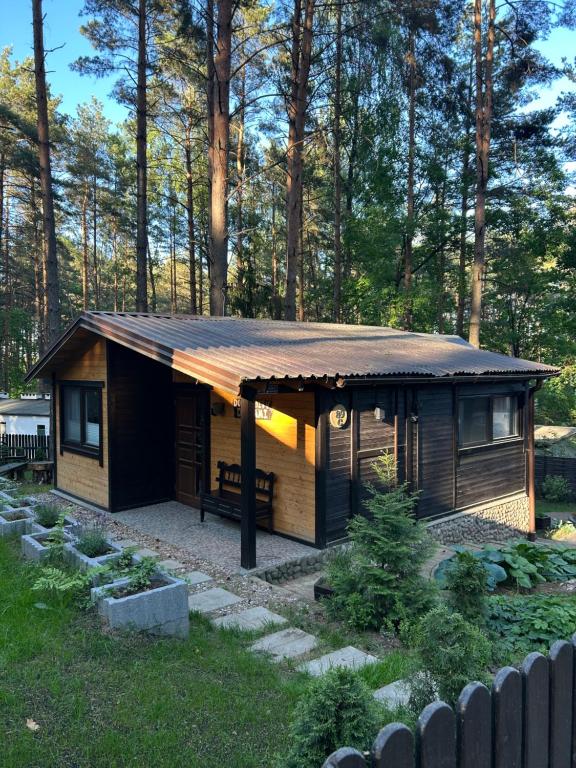 a small cabin with a rusty roof in a yard at Domek obity dechami in Hartowiec