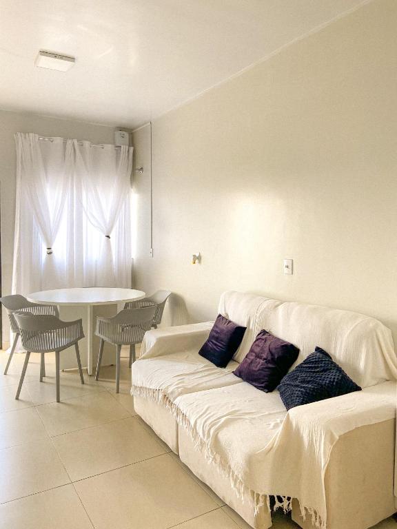 a living room with a white couch with purple pillows at Pousada Acessus Work - Proximo da UniEvangelica e Hospital HEANA in Anápolis