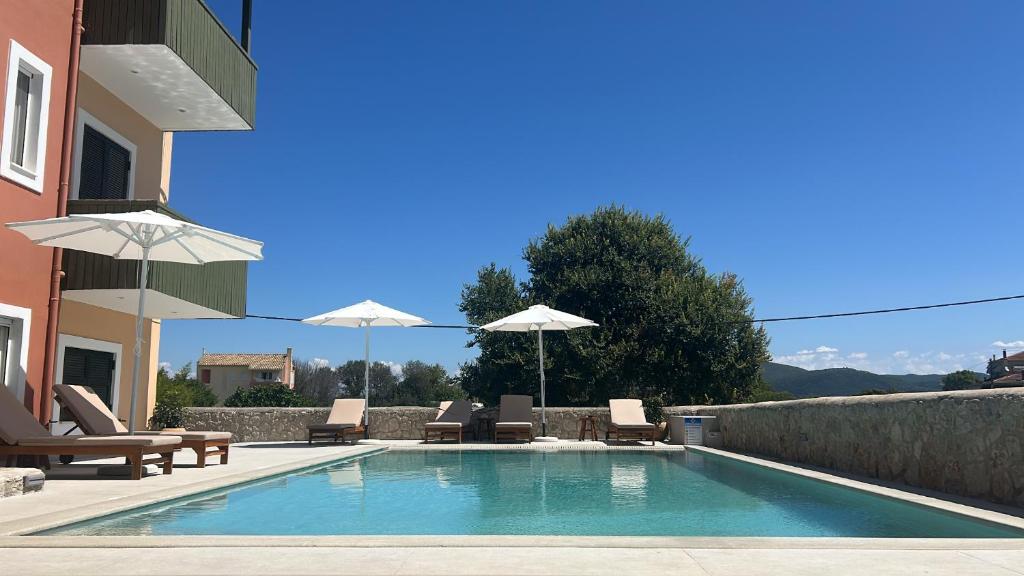 a swimming pool with chairs and umbrellas next to a house at Porto Nirikos Lefkada in Lefkada