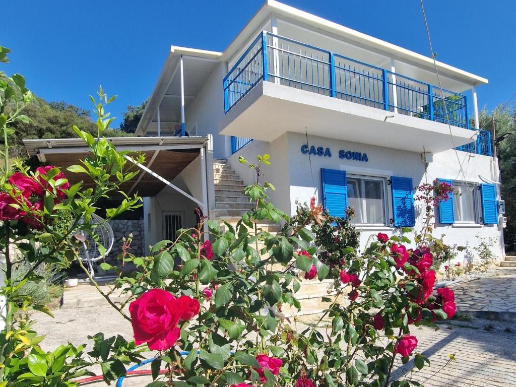 a white house with red roses in front of it at Casa Sonia in Áyios Pétros