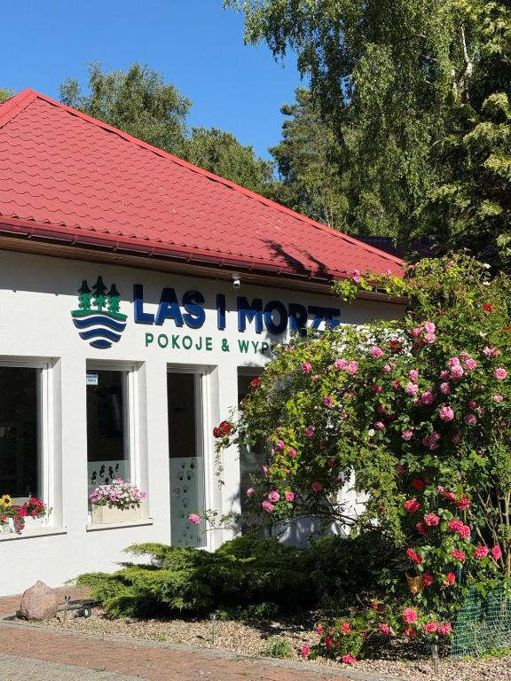 a store with a flowering bush in front of a building at Las i Morze - Dźwirzyno in Dźwirzyno
