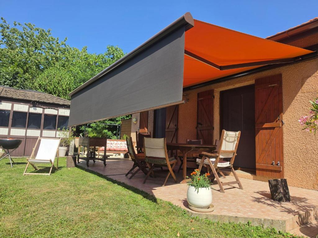 a patio with chairs and an orange umbrella at KERJEANNE in Cailloux-sur-Fontaines