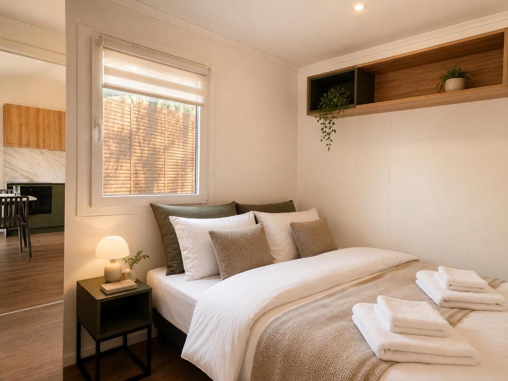 a bedroom with a large white bed with a window at Domki nad rzeką Narew in Ploski