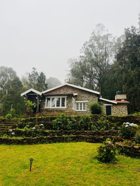 a house on a hill with a field in front of it at Springdale Villa in Kodaikānāl
