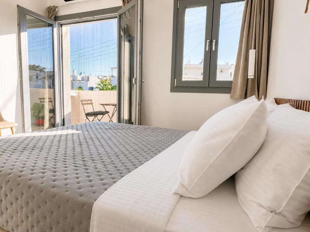 ein Schlafzimmer mit einem weißen Bett und einem großen Fenster in der Unterkunft Aqualis in Adamas