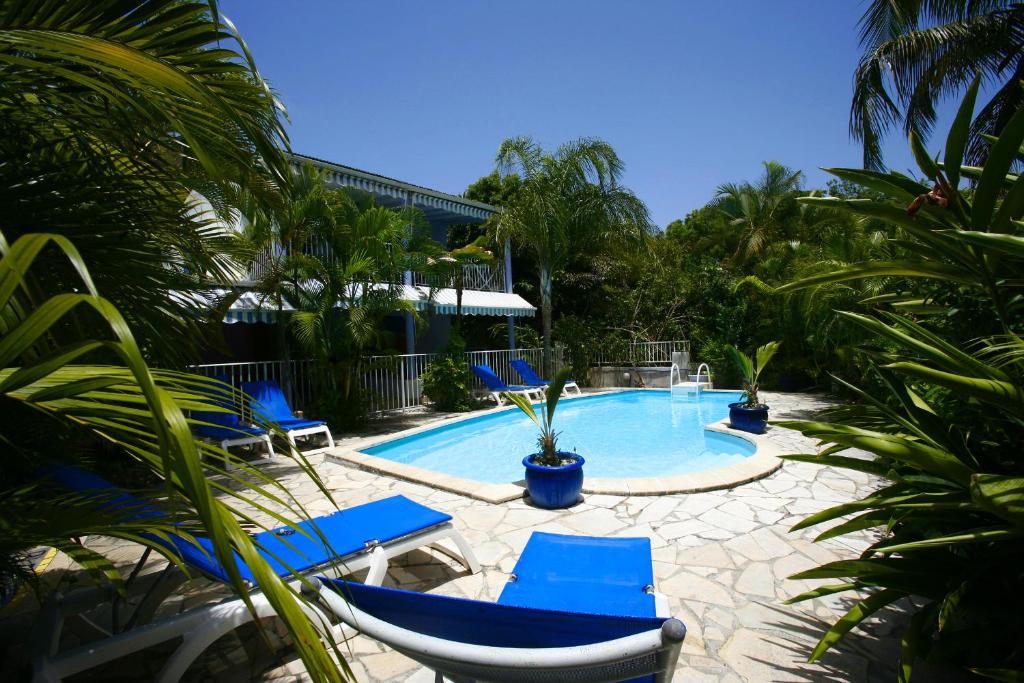 una piscina con sedie blu e palme di Blue Paradise a Le Gosier