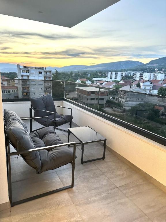 a balcony with two chairs and a table and a view at Apartment Niko in Posušje