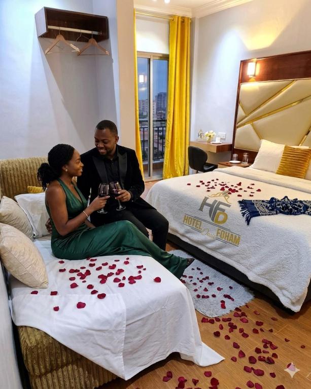 a man and a woman sitting on a bed with roses at Hôtel Foham Oasis in Bandjoun