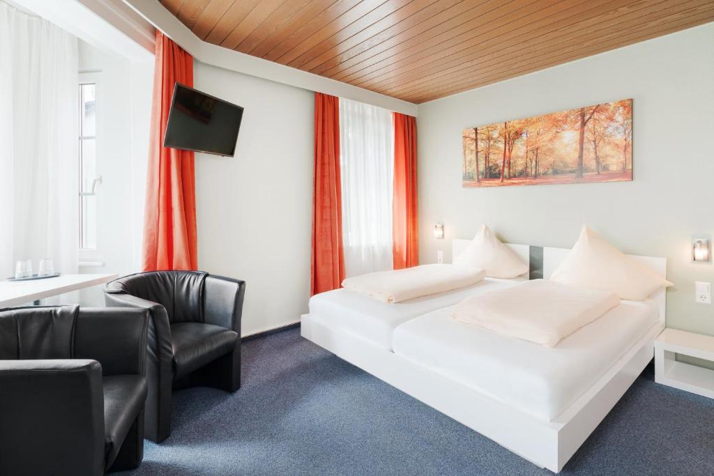 a bedroom with a white bed and a chair at Hotel Romäus in Villingen-Schwenningen