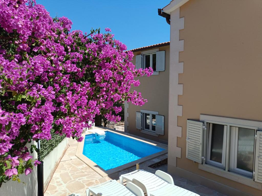 a villa with a swimming pool and purple flowers at Apartments Listes in Milna