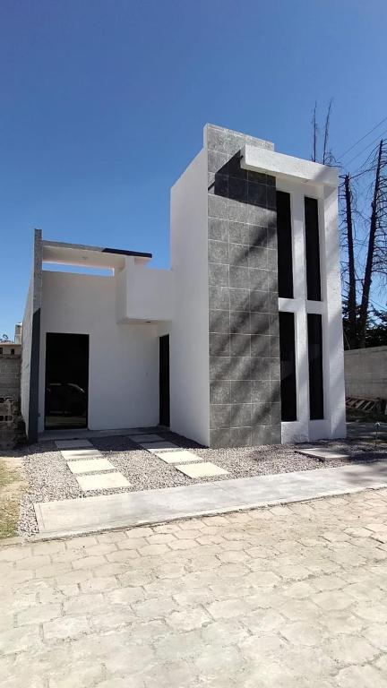 a white church with a cross on the side of it at Casa Las Luces in Nanacamilpa