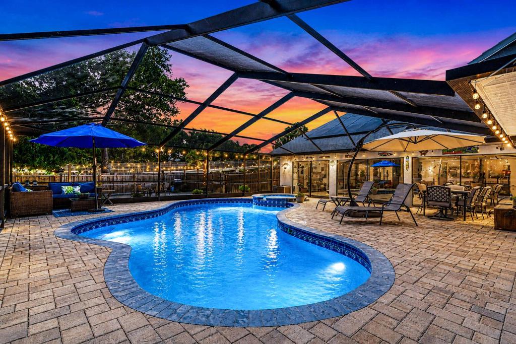 a swimming pool with a patio with tables and umbrellas at Paradise On Park in Seminole