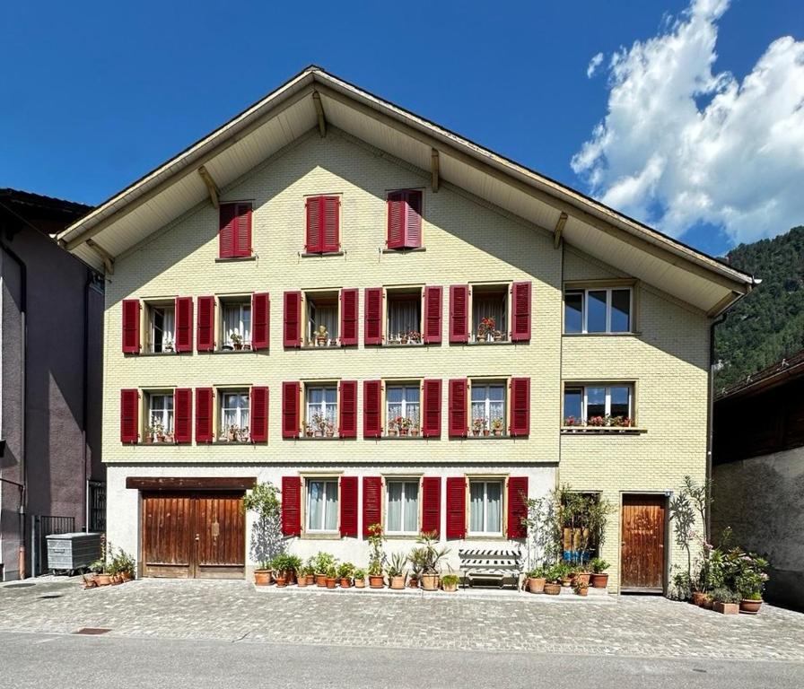 a large house with red shutters on the side of it at Flowerpot Apartment in Unterseen