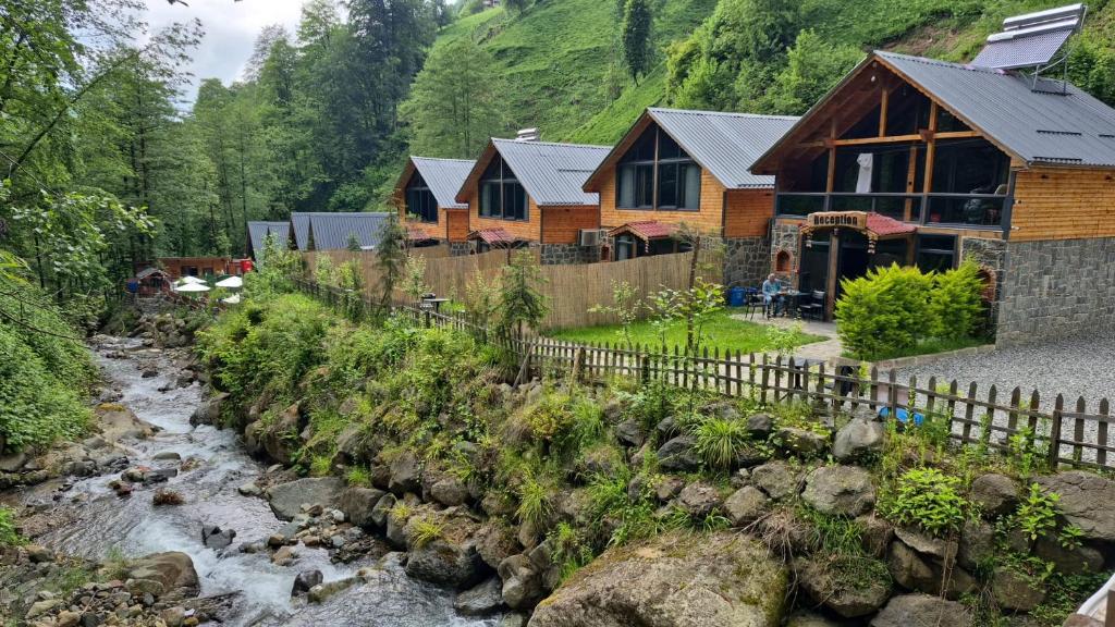 a log house with a stream in front of it at River Villas Resort in Çamlıhemşin