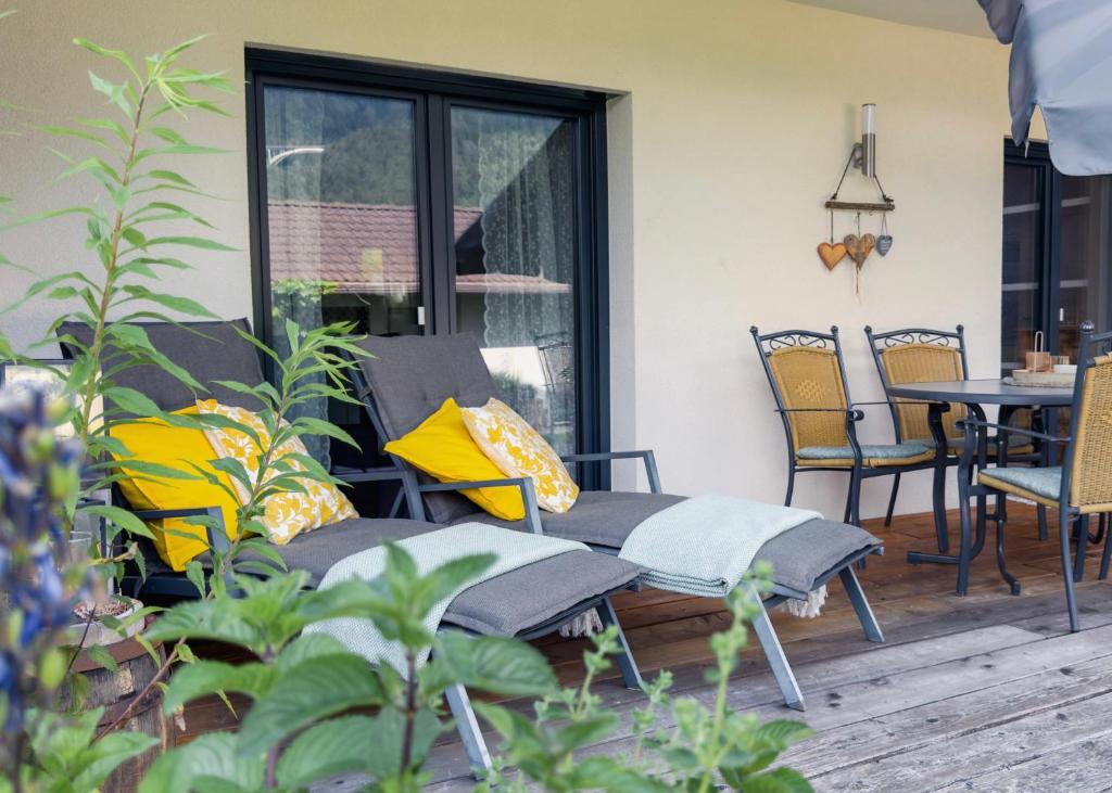 a patio with a bench and a table and chairs at Apartment Danielsbergblick in Napplach