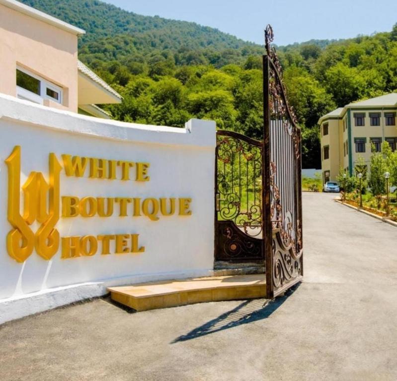 a sign for a white boutique hotel with a gate at WhiteHotelGabala in Gabala