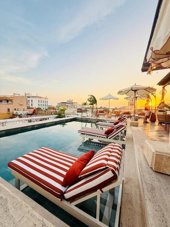 a row of lounge chairs next to a swimming pool at NH Royal Urban Cartagena in Cartagena de Indias