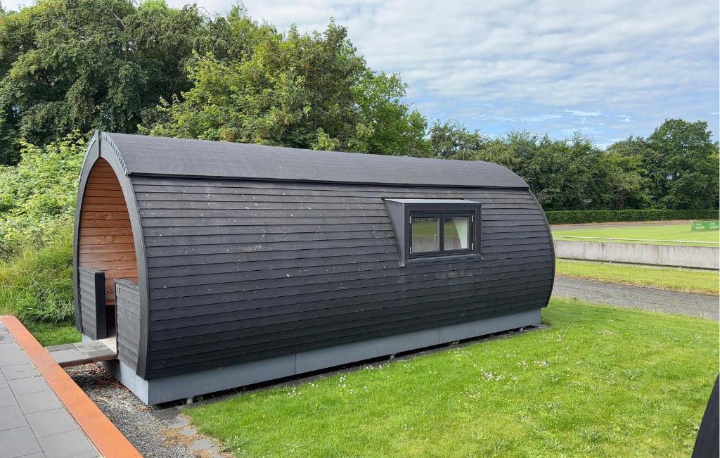 a black building with a window on the grass at Amazing Home In Skjern in Skjern