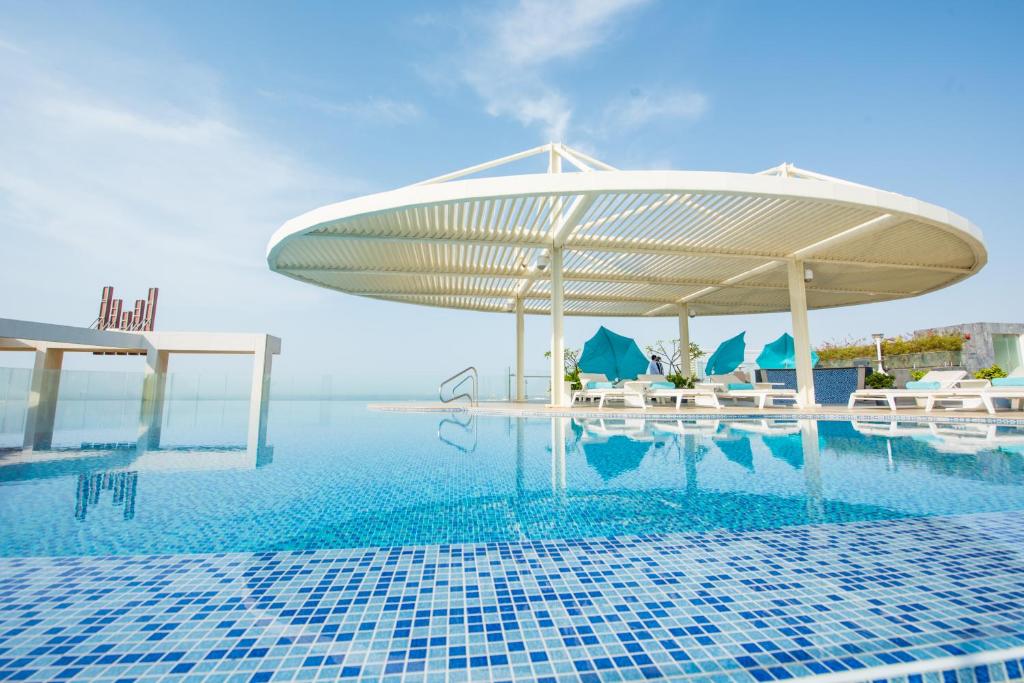 a pool with a pavilion and chairs and a swimming pool at Grand Millennium Muscat Apartments and Suites connected to Mall in Muscat
