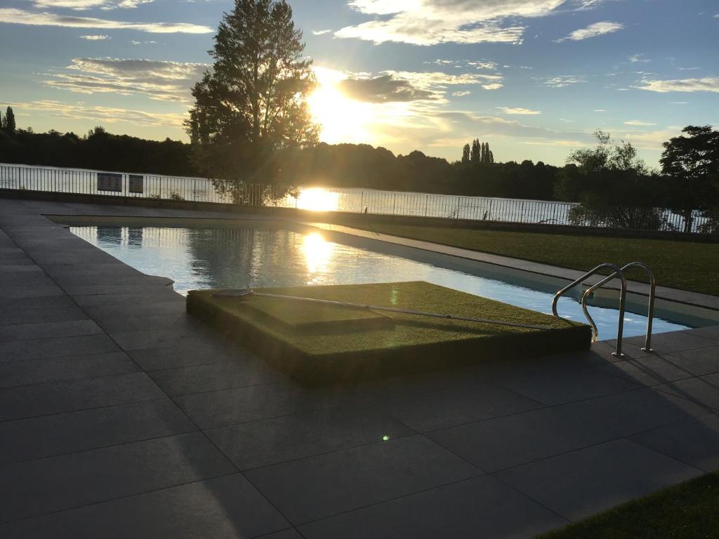 a swimming pool with the sun setting in the background at Apartmany BlueWave Riverside Piešťany in Banka