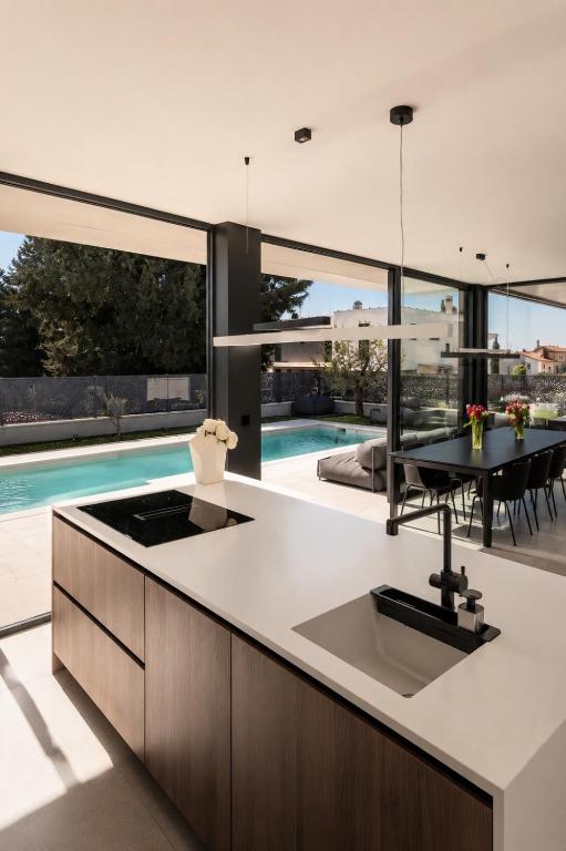 an open kitchen and dining area with a view of a pool at Villa9eleven in Novigrad Istria