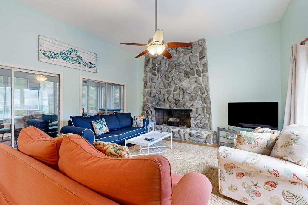 a living room with a couch and a stone fireplace at Teal Haven in Ocean Pines