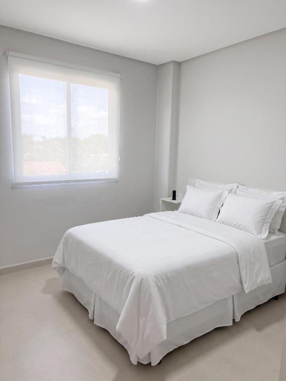 a white bedroom with a large white bed with a window at Laguna Sun Set in Salinópolis