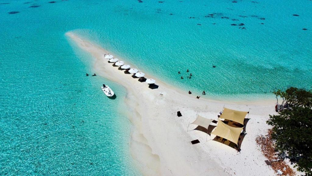 an island with a boat in the water at White Maakana Lodge Maldives - all inclusive ed escursioni incluse ogni giorno in Felidhoo 