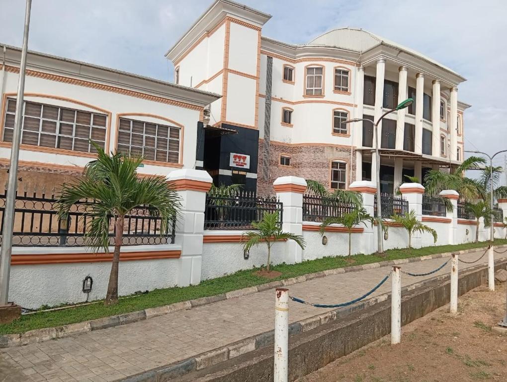 a large white building with palm trees in front of it at Zeus Paradise Hotel Abuja in Abuja