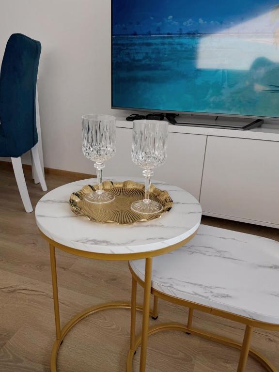 two wine glasses on a table with a tv at LUMA Campus Studio in Brčko
