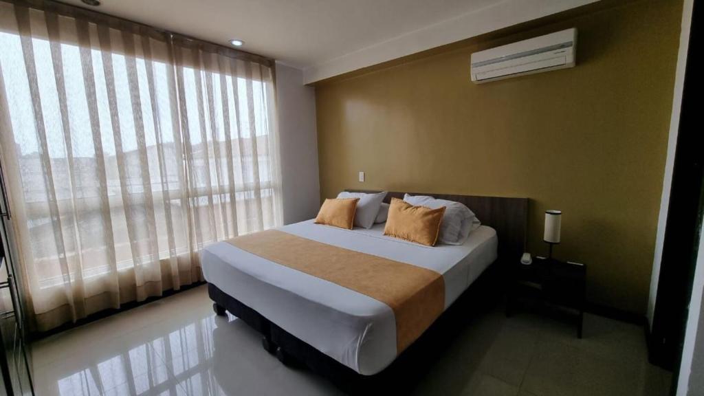 a bedroom with a bed and a large window at Hotel Mare Apartasuite in Cali
