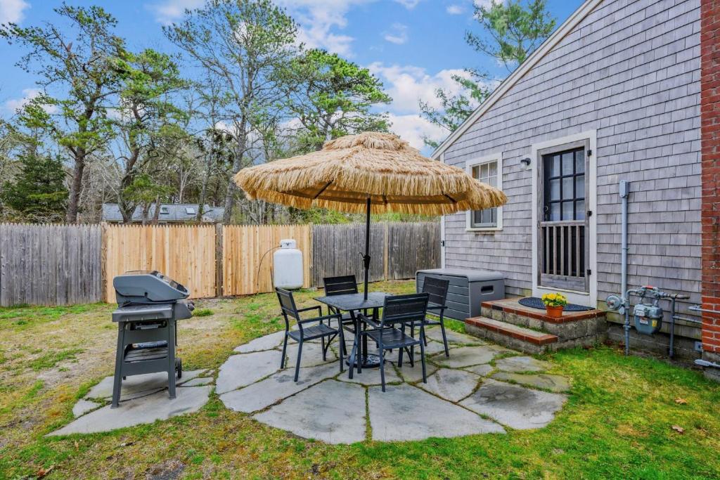 a patio with a table and a grill and an umbrella at Charming Cape Cottage in Dennis Port in Dennis Port