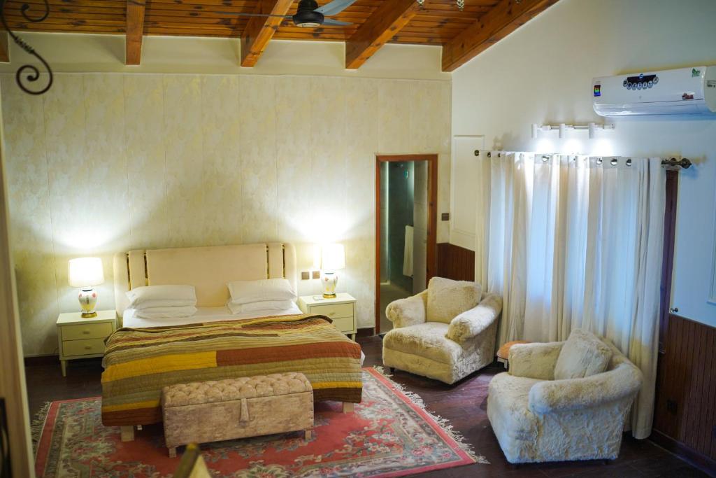 a bedroom with a bed and two chairs in it at Valea Bhurban in Bhurban