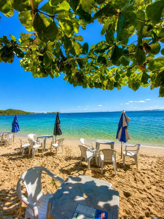 a group of chairs and tables on a beach at TOP 1 QUARTO com ESTACIONAMENTO em Condomínio com VISTA INCRIVEL - PORTARIA 24h, PISCINA, Sauna e Parquinho Infantil - Apartamento com Ar condicionado, Smart TV, Wi-Fi, Cozinha Completa, NETFLIX, Entre o MAR e a LAGOA, CUSTO BENEFICIO in São Pedro da Aldeia