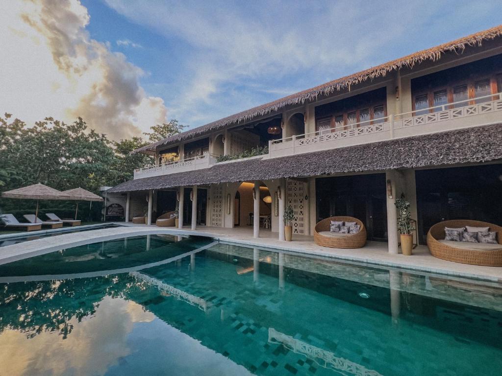 a villa with a swimming pool in front of a building at Schönhouse Villa Siargao in General Luna