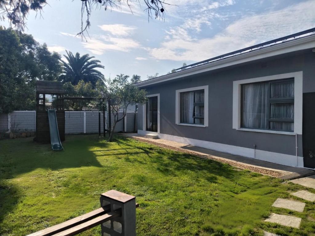 a house with a yard with a bench in front of it at Garden Route Retreat in George