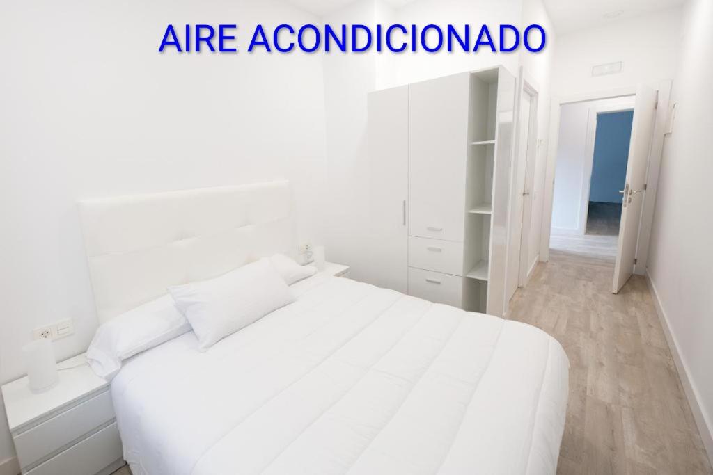 a white bedroom with a white bed and a closet at Pension MD in San Sebastián