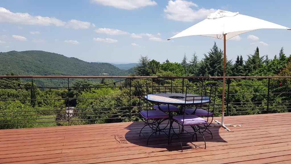 a table and two chairs and an umbrella on a deck at Au Royaume des Chats in Soudorgues