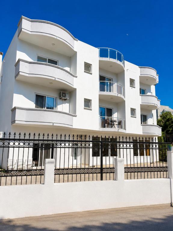 a white building with a fence in front of it at Duraku Apartments in Ulcinj