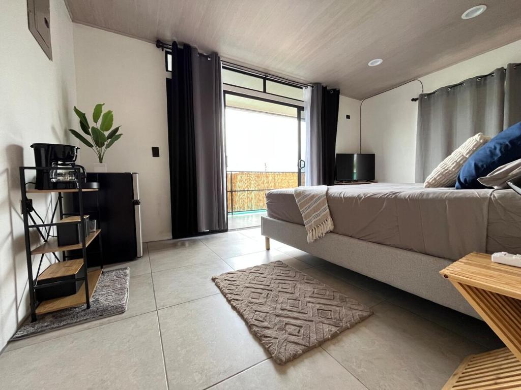 a living room with a bed and a large window at Altima Arenal Volcano View in Tanque