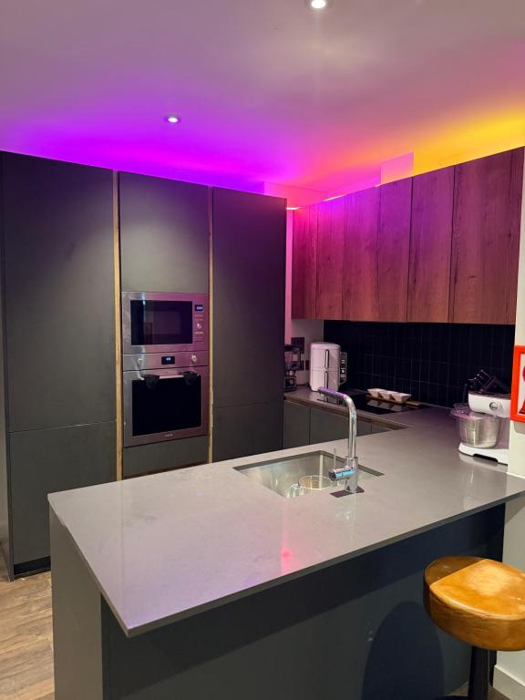 a kitchen with a white counter and purple lighting at Greenford Quay in Harrow on the Hill