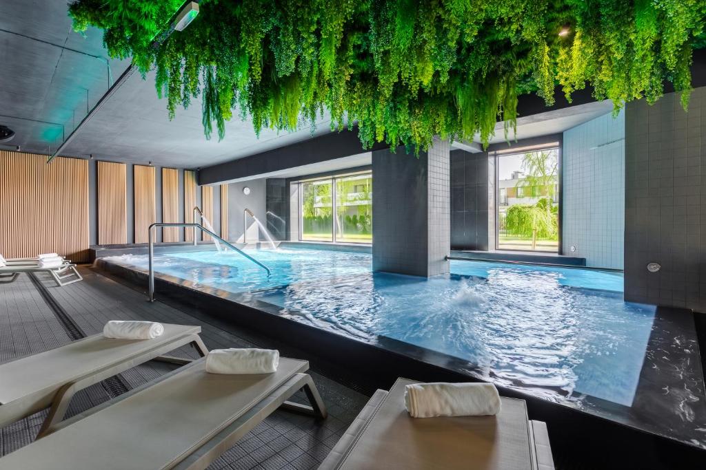 a large swimming pool with two tables and chairs at Villa Verdi Pleasure & Spa in Łeba