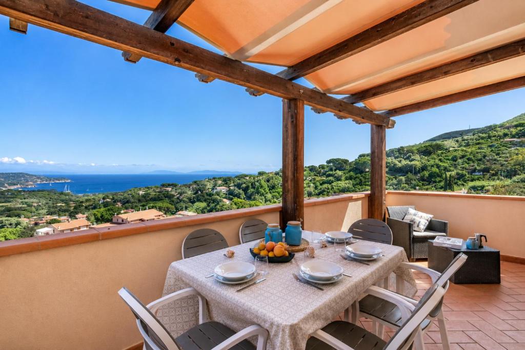 a table and chairs on a balcony with a view of the ocean at Casa Andreale in Capoliveri