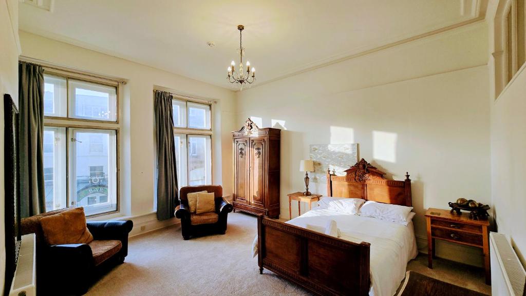 a bedroom with a bed and a chair and windows at Spring View Apartment in Buxton