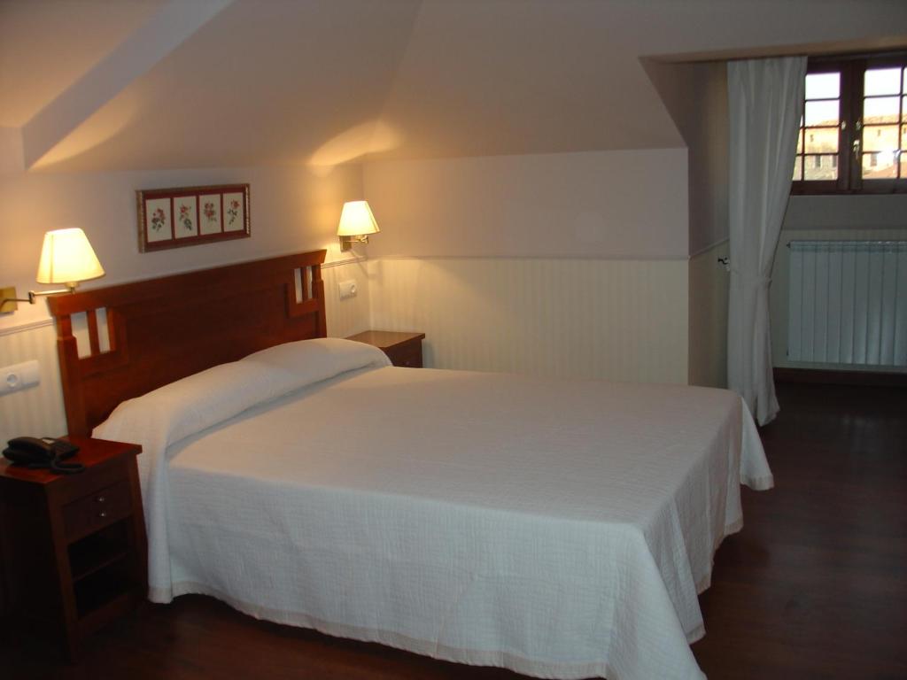 1 dormitorio con 2 camas blancas y ventana en Hospederia el Fielato, en El Burgo de Osma