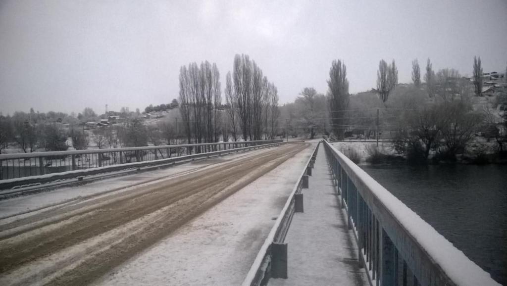 a snow covered road with a bridge and trees at Cabañas El Puente Azul in Aluminé