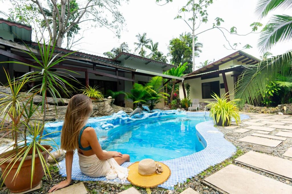 a woman sitting next to a swimming pool at Casa Caribbean Coconut in Cahuita