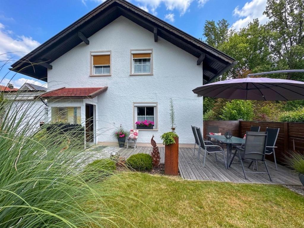 a white house with a table and chairs and an umbrella at Bayerischer Wald in Waldkirchen