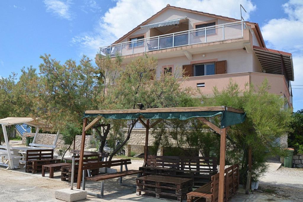 a building with tables and benches in front of a building at Apartments and rooms by the sea Nevidjane, Pasman - 11902 in Neviđane