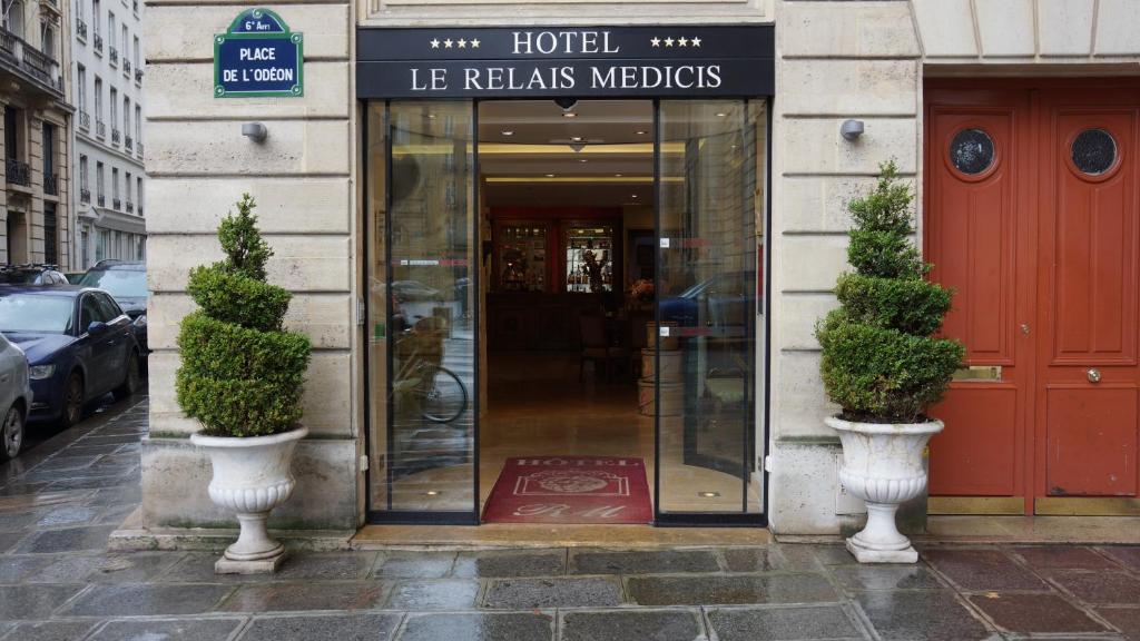 une entrée à un hôtel avec deux plantes en pot devant dans l'établissement Le Relais Médicis, à Paris